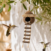 Hangend vogelhuisje van kokosnoot met dak van stro