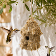 Hangend vogelhuisje van stro met dak van riet